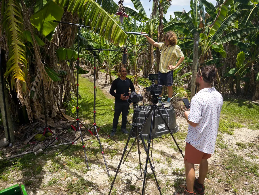 A Now We Know TV! interview underway between rows of tropical fruit trees at Miami Fruit